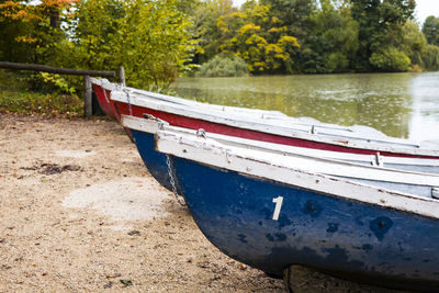 Boat moored on shore by lake