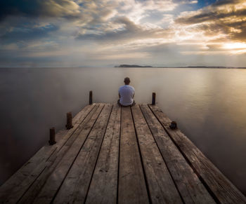 Rear view of man sitting on pier