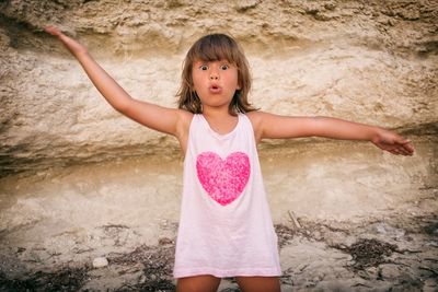 Portrait of shocked girl gesturing while standing by rock formation