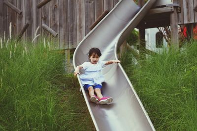 Rear view of boy on slide at park