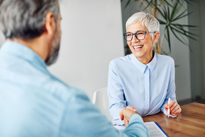 Smiling woman shaking hands with coworker at table