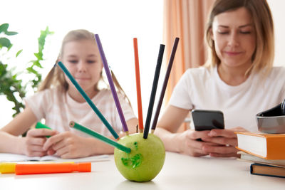 Mother and daughter sitting by desk at home