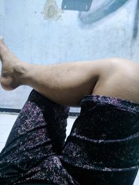 Low section of woman sitting by swimming pool