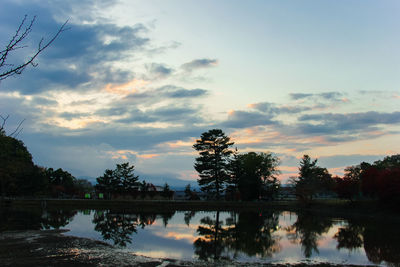 Silhouette trees by lake against sky during sunset