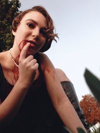 Close-up of young woman looking away against clear sky