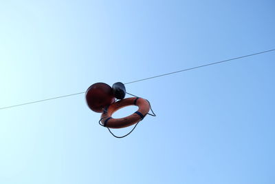 Low angle view of life belt hanging against clear blue sky