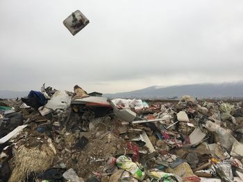 Stack of garbage by metal structure against sky