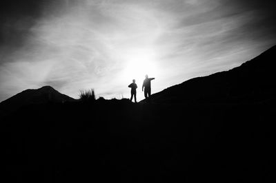 Silhouette man standing on mountain against sky