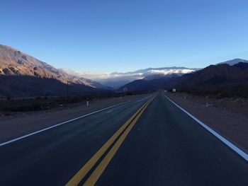 Road by mountains against clear blue sky