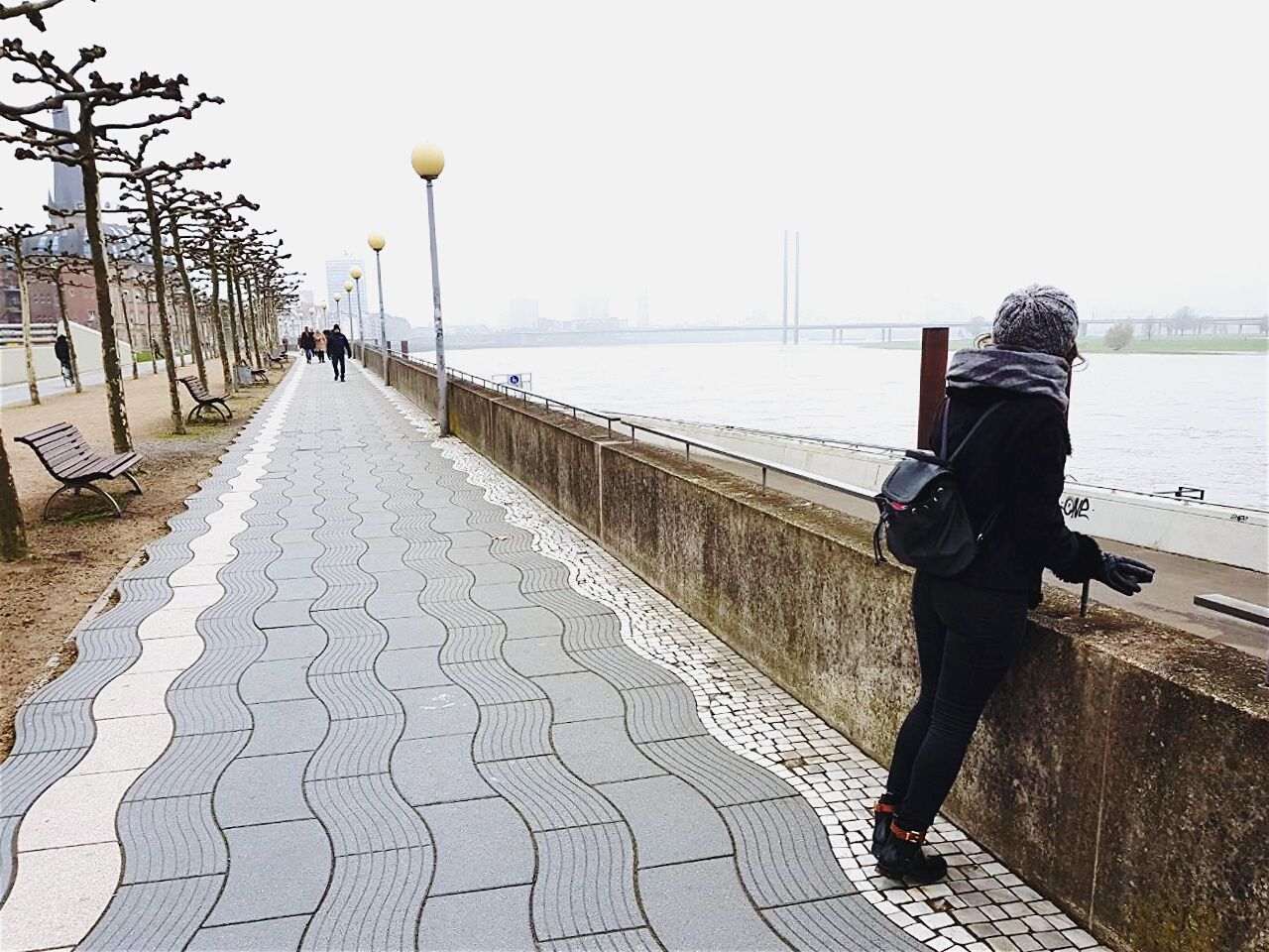 full length, footpath, water, railing, outdoors, day, walking, sidewalk, built structure, rear view, real people, one person, clear sky, sea, sky, architecture, city, nature, tree, adult, people, adults only