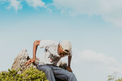 Man sitting by plants against sky