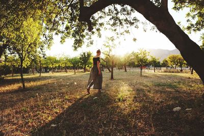 Woman standing on field against trees