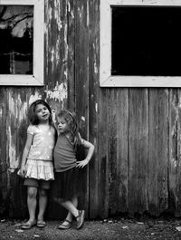 Full length of sisters standing against abandoned building