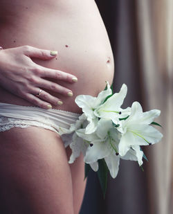 Midsection of woman standing by flowers