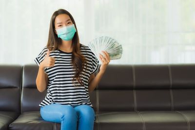 Full length of woman sitting on sofa at home