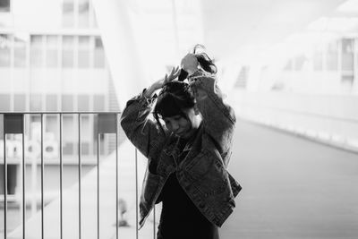 Woman wearing hat standing against built structure