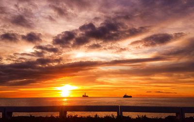 Scenic view of sea against dramatic sky during sunset