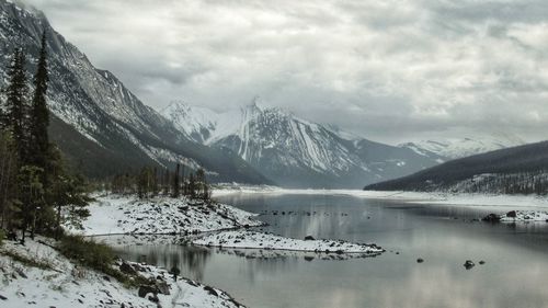 Scenic view of lake by snowcapped mountains against sky
