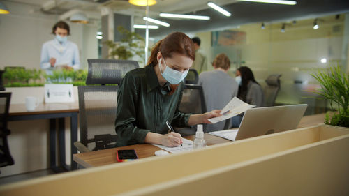 Young businesswoman wearing mask working at office