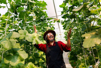 Smiling farmer standing against plants