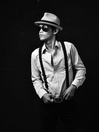 Portrait of young man wearing hat against black background