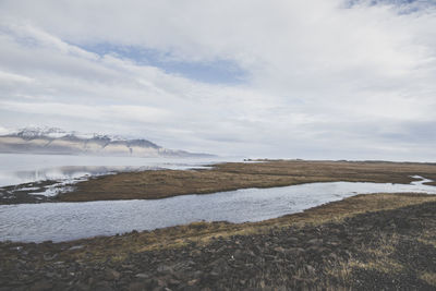 Scenic view of landscape by sea against sky