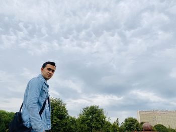 Portrait of young man standing against sky