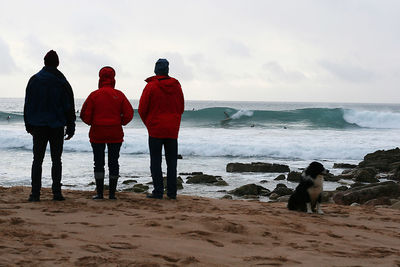 Rear view of people on beach against sky