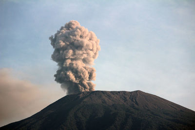 Smoke emitting from volcanic mountain against sky - slamet mount