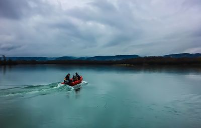 Men sitting on boat in river against sky