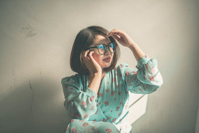 Woman shielding eyes against wall