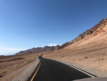 Road amidst landscape against clear blue sky