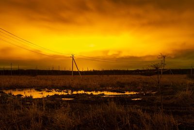 Electricity pylon on field against romantic sky at sunset