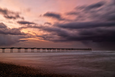 Bridge over sea against sky during sunset