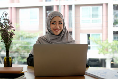 Young woman with laptop sitting at desk