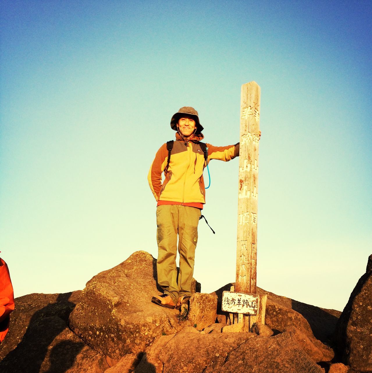 lifestyles, young adult, casual clothing, leisure activity, person, full length, young men, clear sky, standing, copy space, front view, rock - object, looking at camera, portrait, smiling, sunglasses