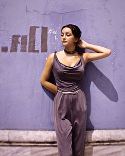 Portrait of a young woman standing against wall