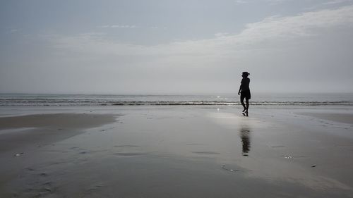 Full length of man walking on beach against sky