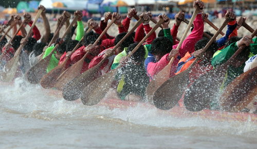 People oaring boat in river