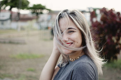 Smiling young woman with blond hair in park