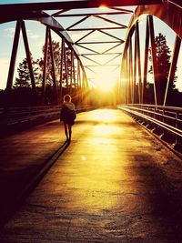 Rear view of man on bridge against sky during sunset