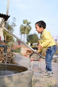 Boy playing with hand pump in village