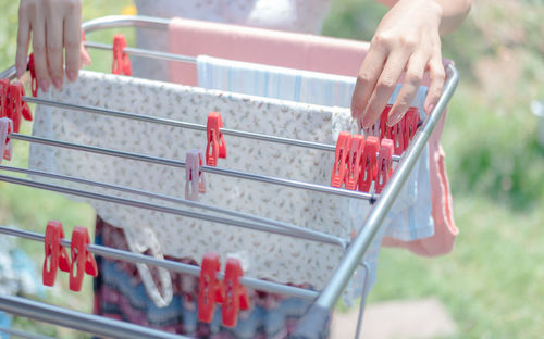 Cropped image of woman drying clothes from laundry rack