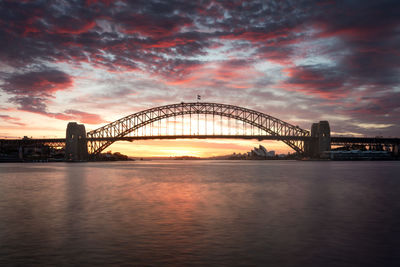 Illuminated bridge over river against sky at night