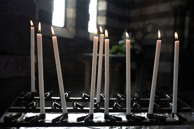 Burning candles glowing in dark isolated on black church