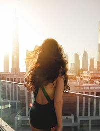 Woman standing on railing against buildings in city