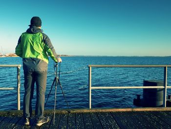 Alone artist on wooden sea bridge. photographer with with mirror camera and tripod at end of pier