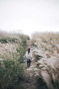 Woman walking on snow covered landscape against sky