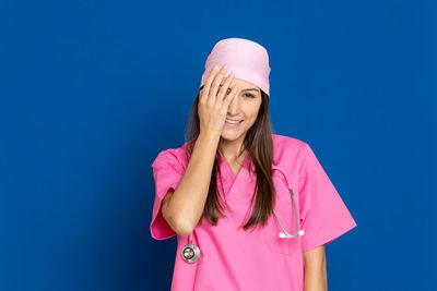 Portrait of young woman standing against pink blue background