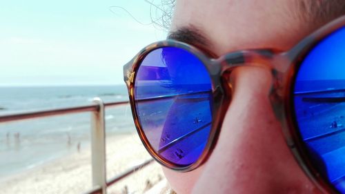 Close-up of hand holding eyeglasses against sea